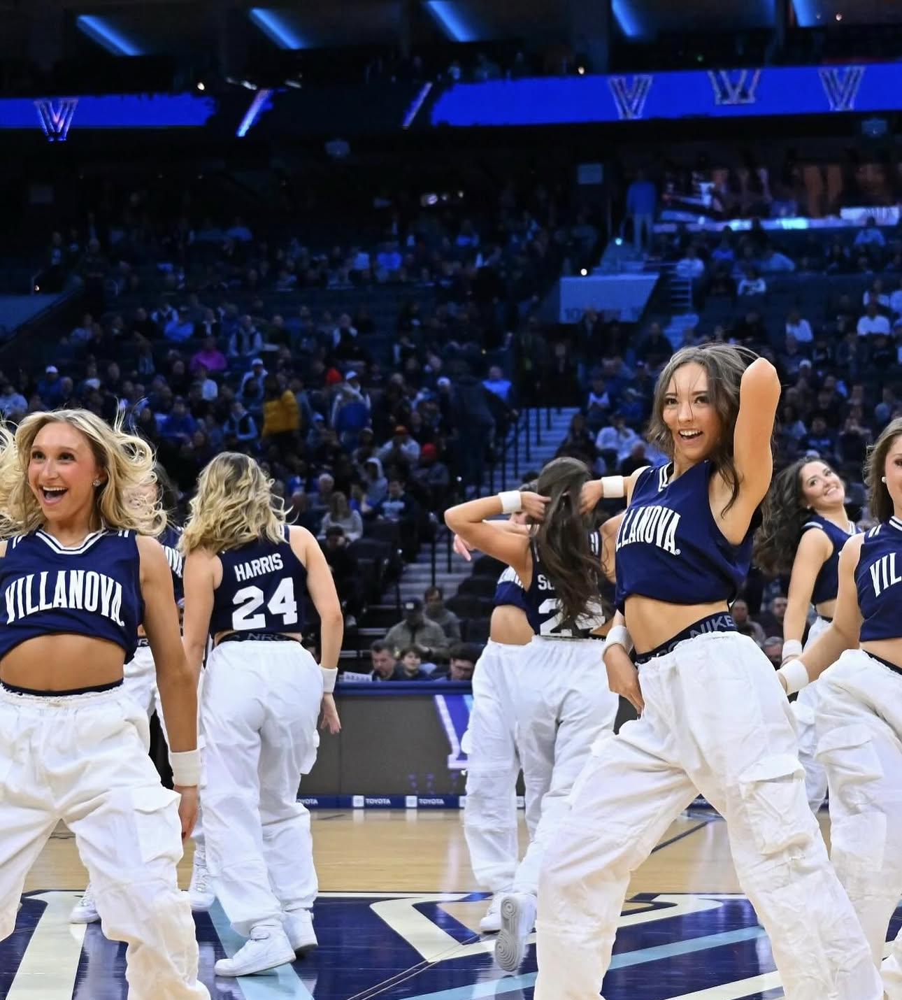 College dance team performing in navy uniforms on the court